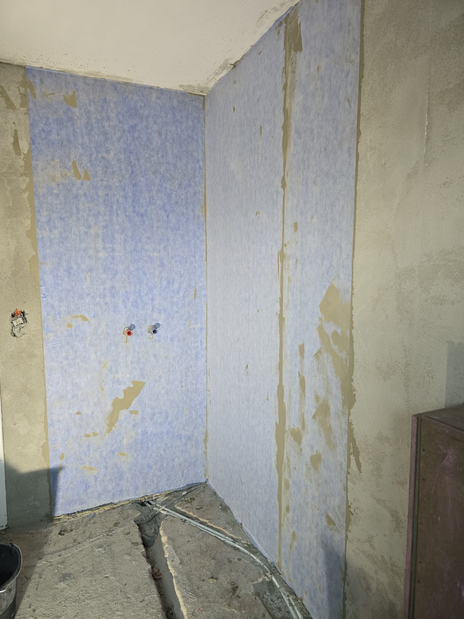 Voor-beeld: badkamerwand tijdens de renovatie, met vrijgemaakte leidingen