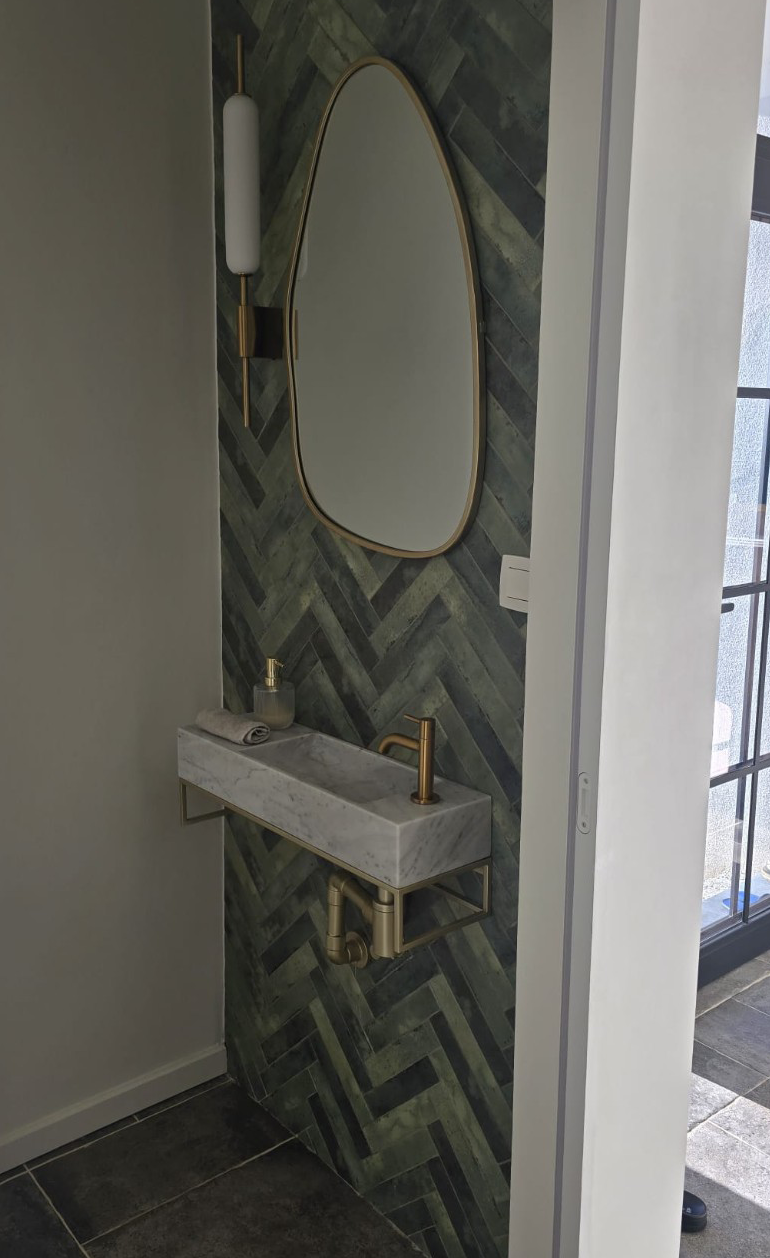 Voor-beeld: lavabo en ovale spiegel tegen een wand met visgraattegels